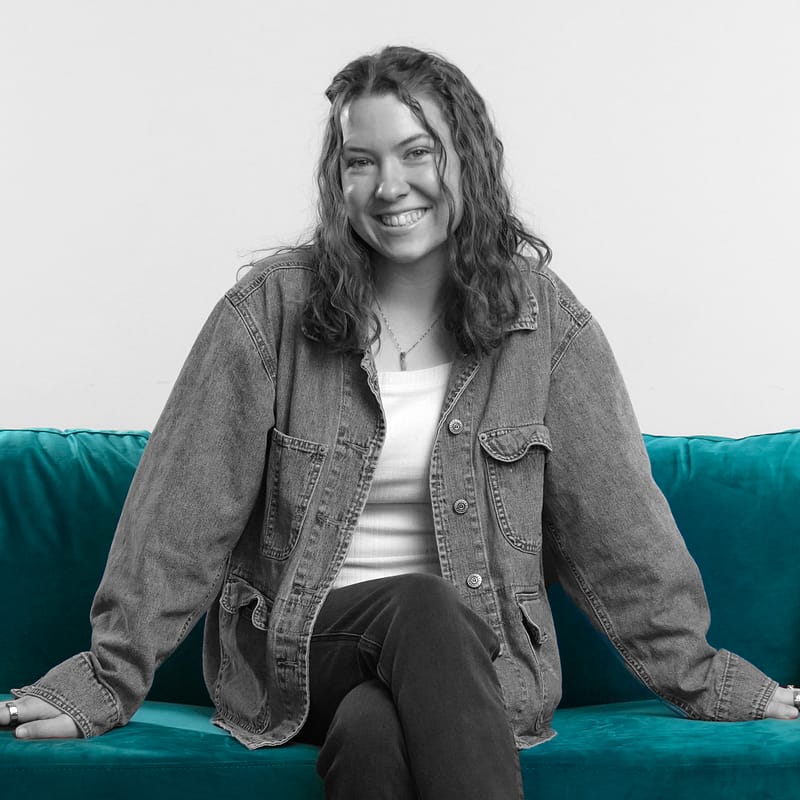 A photo of Callie Herring, NEI's marketing content producer, on a blue couch.